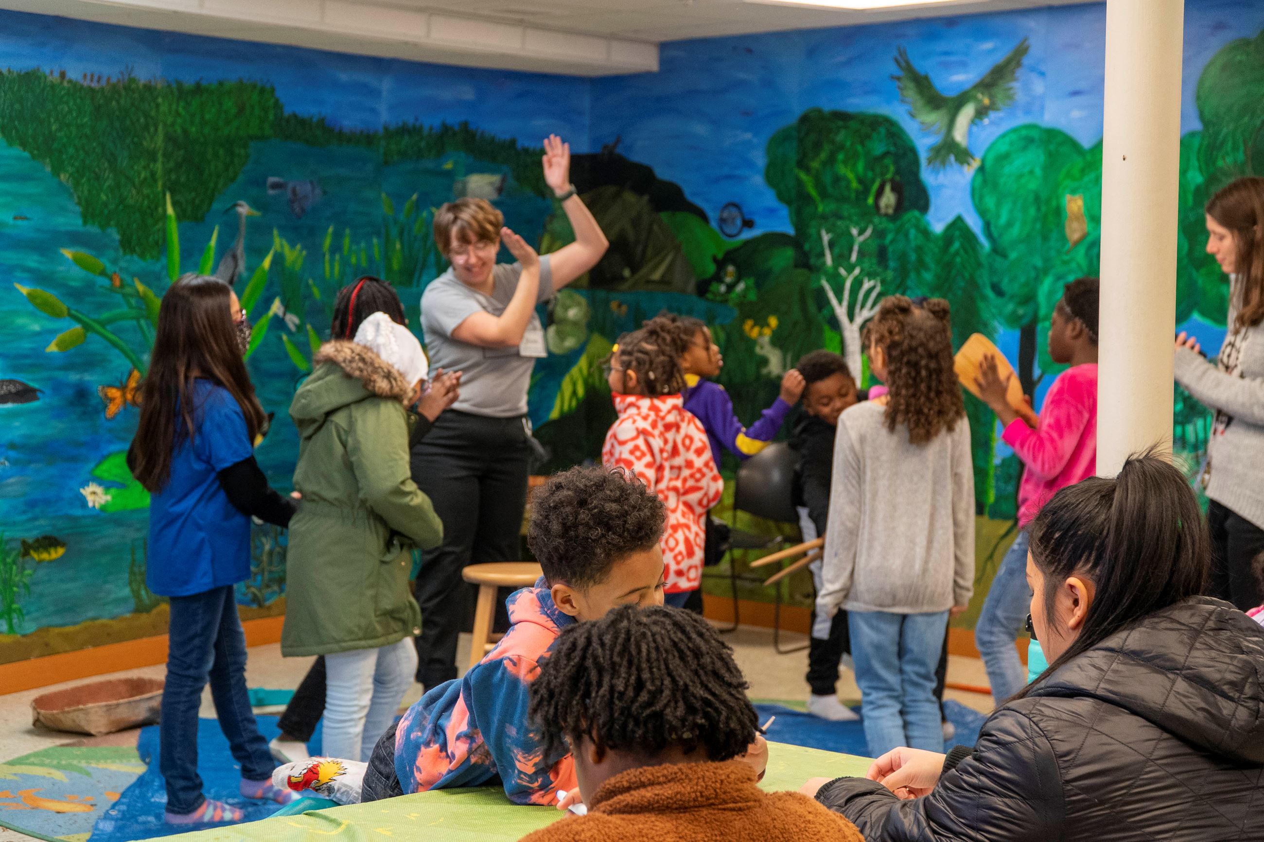 Students do Native American-inspired craft projects and dance in the background.
